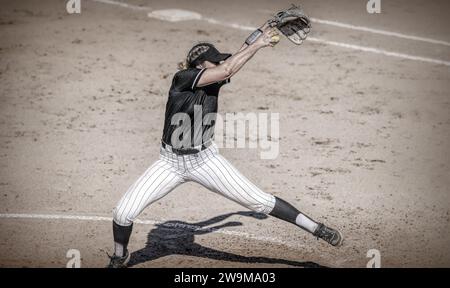 Ein weiblicher Softball-Spieler ist in Full Windup Pitching Antik Grainy Monochrom Stockfoto