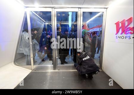 New York, USA. Dezember 2023. Ein Mitglied der Port Authority Police schließt die Südtür des Oculus ab, während eine Gruppe pro-palästinensischer Demonstranten in der Nähe der Gedenkstätte 9/11 in New York, NY, 28. Dezember 2023 spazieren geht. (Foto: Anthony Behar/SIPA USA) Credit: SIPA USA/Alamy Live News Stockfoto