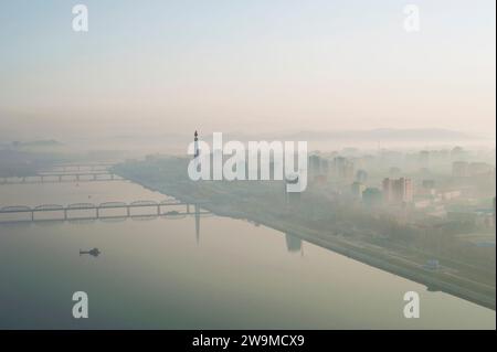 Der Blick auf den Taedong-Fluss und den Juche-Turm in Pjöngjang in Nordkorea während eines nebeligen Sonnenaufgangs am frühen Morgen. Stockfoto