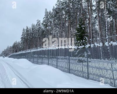 Silene, Lettland. Dezember 2023. Die Straße am Grenzzaun an der Lettisch-belarussischen Grenze ist mit tiefem Schnee bedeckt. Lettland hat eine etwa 172 Kilometer lange Grenze zu Russlands engstem Verbündeten Belarus, das Teil der EU-Außengrenze ist. (An dpa "Lettland: Zaun an der Grenze zu Belarus nähert sich der Fertigstellung") Credit: Alexander Welscher/dpa/Alamy Live News Stockfoto