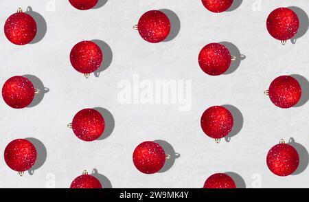 Kreatives trendiges Muster mit roten Weihnachtskugeln auf verschneiten Hintergrund mit Kopierraum. Minimales Weihnachts- oder Neujahrskonzept. Winter-Idee. Stockfoto