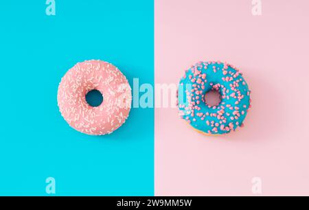 Rosa und blau glasierte Donuts auf hellblauem und pastellrosa Hintergrund. Kreatives Konzept. Minimalistisch leckeres Essen. Flache, leckere Donut-Komposition. Stockfoto