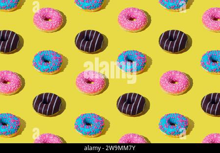 Kreatives Muster von bunten Donuts auf hellgelbem Hintergrund. Minimales Konzept. Trendiger Hintergrund mit Donuts-Muster. Leckere Essenszusammensetzung. Stockfoto