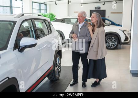 Ein älteres kaukasisches Paar wählt ein neues Auto in einem Autohändler. Stockfoto