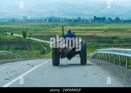 Alter Mann, der Traktor fährt, auf der Straße. Querformat. Auf Dem Land. Landschaft. 5. 8. 2023 Sokolarci. Mazedonien Stockfoto