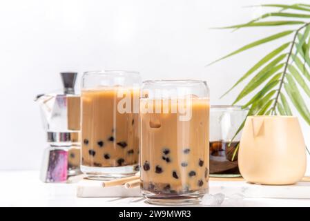 Iced Tapica Coffee Latte oder boba Pearl Bubbles Milchtee, asiatisches trendiges kaltes Kaffeegetränk mit Tapiokasseln und zerstoßenem Eis, auf weißem Marmorhintergrund Stockfoto