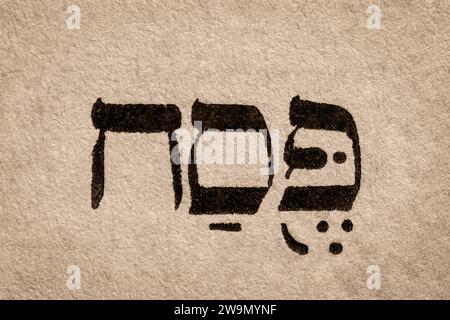 Ein einziges hebräisches Wort Pesach auf der Seite des alten Tora-Buches. Die englische Übersetzung ist Pessach. Jüdischer Feiertag der Israeliten entkommen der Sklaverei in Ägypten. Hebräisch Stockfoto