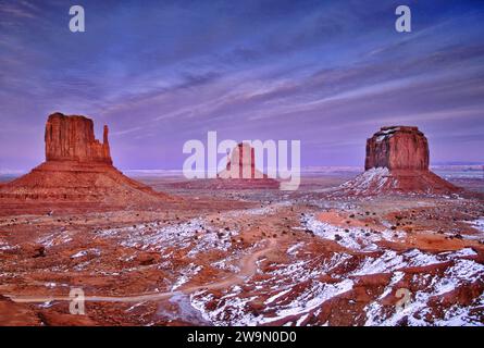 Blick auf West Mitten Butte, East Mitten Butte und Merrick Butte im Monument Valley, Schneeflocken bei Sonnenuntergang im Winter, Arizona, USA Stockfoto