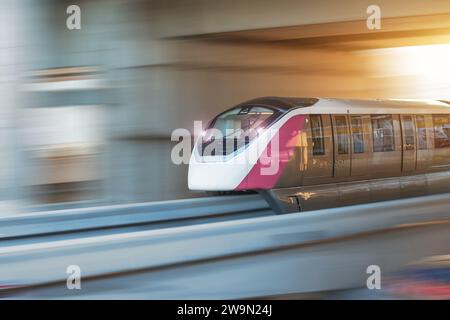 Moderne Hochgeschwindigkeits-Einschienenbahn mit hellen Scheinwerfern fährt am Abend bei Sonnenuntergang auf Bühnenfahrten durch den Tunnel Stadtviadukt vorbei Stockfoto