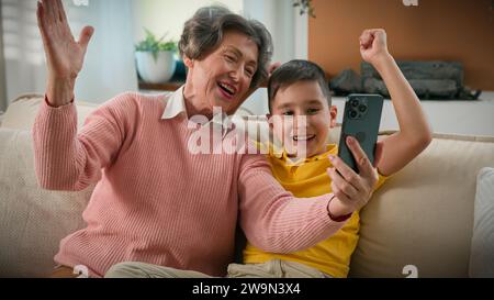Kaukasische Großmutter und Enkel zusammen auf der Heimcouch fotografierten Selfie auf Handy-Narr um lustige Familie zwei Generationen Großmutter machen Stockfoto