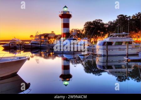 Boote und der Leuchtturm spiegeln sich im Harbour Town Marina bei Sonnenuntergang auf Hilton Head Island, SC. Stockfoto