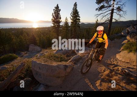 Eine Frau, die bei Sonnenuntergang auf dem Van Sickle Trail mit Lake Tahoe im Hintergrund in South Lake Tahoe, CA. Stockfoto