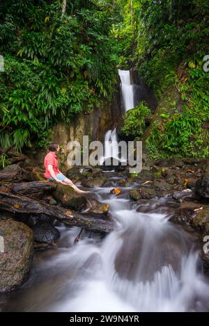 Eine Frau entspannt sich an einem wunderschönen Wasserfall in Trafalgar am Papillote Wilderness Retreat am Ende des Segments 3 des Waitukubuli National Trail auf der Karibikinsel Stockfoto