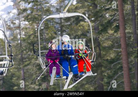 Zwei junge Skifahrer fahren mit ihrem Skilehrer in den Sessellift, während sie eine Lektion im Kirkwood Mountain Resort in Kirkwood, Kalifornien, nehmen. Stockfoto