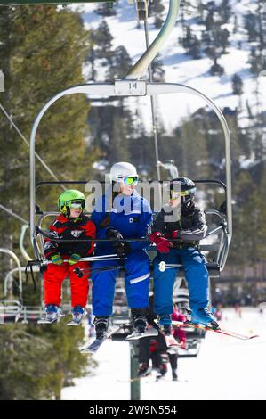 Zwei junge Skifahrer fahren mit ihrem Skilehrer in den Sessellift, während sie eine Lektion im Kirkwood Mountain Resort in Kirkwood, Kalifornien, nehmen. Stockfoto