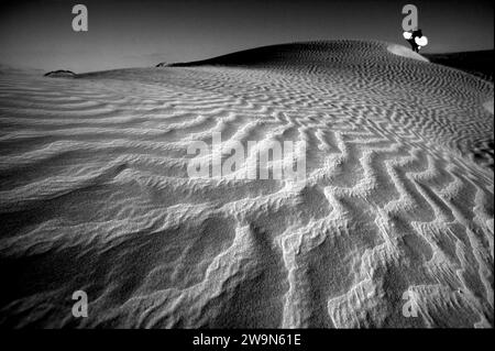 Auf einer Düne steht ein einsames Surferbrett, das Sonnenlicht in der Magdalena Bay, Mexiko, reflektiert. Stockfoto