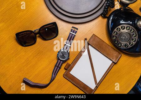 Uhr, analoges Telefon und Notizblock auf dem Nachttisch Stockfoto