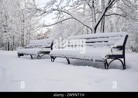 Mit reinweißem Schnee bedeckte Bänke in einem Stadtpark Stockfoto