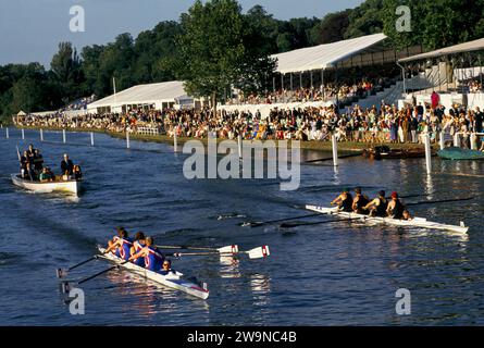Sommer England Ruderregatta UK. Henley Royal Regatta. Die Siegersportler beobachten das Ruderrennen vom Ufer der Tribüne aus. Das Judges Boat folgt den beiden Mannschaftsbooten, während sie die Ziellinie überqueren. Henley on Thames, Oxfordshire, Juli 1995 1990, UK HOMER SYKES Stockfoto