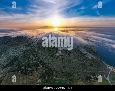 Sizilien 2023. Wolken, die über den Mount Santa Caterina auf der Insel Favignana klettern. Dahinter sehen wir die Sonne bei Sonnenaufgang. Juli 2023 Trapani, Italien Stockfoto