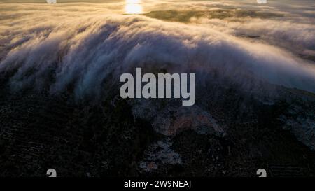 Sizilien 2023. Wolken, die über den Mount Santa Caterina auf der Insel Favignana klettern. Dahinter sehen wir die Sonne bei Sonnenaufgang. Juli 2023 Trapani, Italien Stockfoto