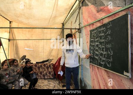 Rafah. Dezember 2023. Studenten studieren in einem temporären Klassenzimmer in Rafah im südlichen Gazastreifen am 28. Dezember 2023. Einige Schüler in Gaza haben in vorübergehende Klassenzimmer umgestiegen, da viele Schulen hier für die Unterbringung von Obdachlosen genutzt werden, die durch eine neue Runde des palästinensisch-israelischen Konflikts verursacht wurden. Quelle: Rizek Abdeljawad/Xinhua/Alamy Live News Stockfoto