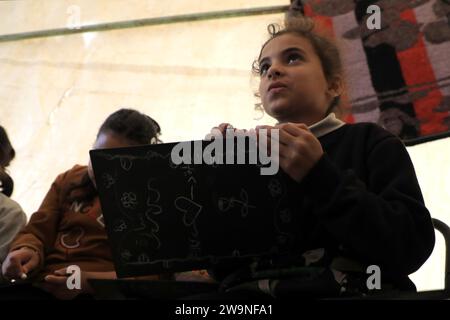 Rafah. Dezember 2023. Studenten studieren in einem temporären Klassenzimmer in Rafah im südlichen Gazastreifen am 28. Dezember 2023. Einige Schüler in Gaza haben in vorübergehende Klassenzimmer umgestiegen, da viele Schulen hier für die Unterbringung von Obdachlosen genutzt werden, die durch eine neue Runde des palästinensisch-israelischen Konflikts verursacht wurden. Quelle: Rizek Abdeljawad/Xinhua/Alamy Live News Stockfoto