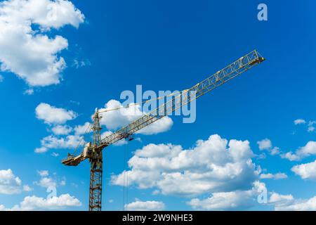 Gelber Hochbaukran vor dem Hintergrund des Sonnenuntergangs bewölkten Himmels. Stockfoto