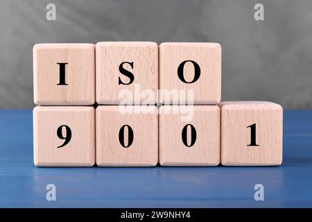 Internationale Organisation für Normung. Würfel mit der Abkürzung ISO und der Nummer 9001 auf blauem Holztisch Stockfoto