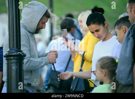 Straßenverkäufer, der das Armband an eine junge Frau verkauft, die Leute beobachtet. 12. September 2020. Kiew, Ukraine Stockfoto