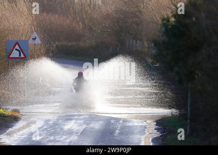 Ein Motorradfahrer, der auf der Newton Lane, Fairburn, North Yorkshire, Großbritannien, durch das Hochwasser gefahren ist Stockfoto