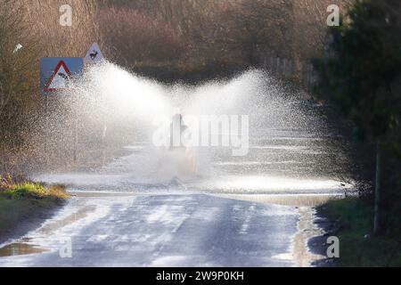 Ein Motorradfahrer, der auf der Newton Lane, Fairburn, North Yorkshire, Großbritannien, durch das Hochwasser gefahren ist Stockfoto