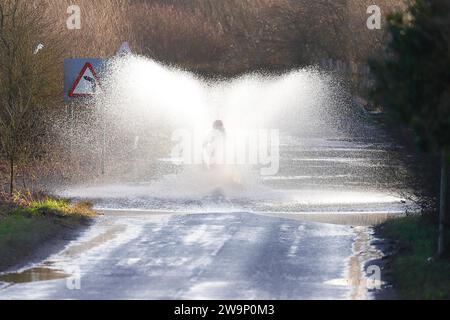 Ein Motorradfahrer, der auf der Newton Lane, Fairburn, North Yorkshire, Großbritannien, durch das Hochwasser gefahren ist Stockfoto