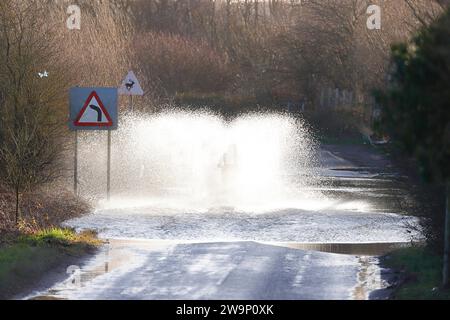 Ein Motorradfahrer, der auf der Newton Lane, Fairburn, North Yorkshire, Großbritannien, durch das Hochwasser gefahren ist Stockfoto