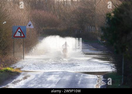 Ein Motorradfahrer, der auf der Newton Lane, Fairburn, North Yorkshire, Großbritannien, durch das Hochwasser gefahren ist Stockfoto