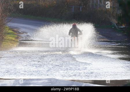 Ein Motorradfahrer, der auf der Newton Lane, Fairburn, North Yorkshire, Großbritannien, durch das Hochwasser gefahren ist Stockfoto