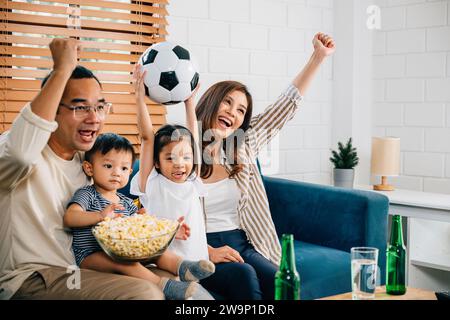 Eine glückliche Familie genießt den Nervenkitzel eines Fußballspiels zu Hause Stockfoto
