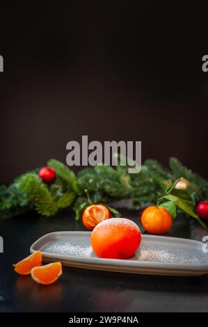 Teller mit köstlichem Mochi und Mandarine auf dunklem Weihnachtshintergrund. Stockfoto