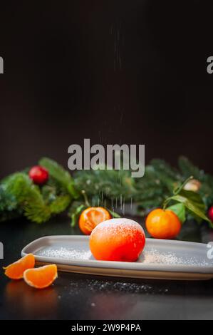 Teller mit köstlichem Mochi und Mandarine auf dunklem Weihnachtshintergrund. Stockfoto