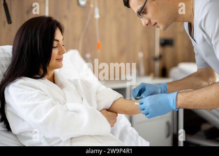 Die Krankenschwester führt einen Katheter bei einer Patientin auf der medizinischen Station ein Stockfoto