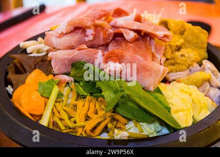 Taiwanesische Küche Hot Pot mit Schweinefleisch, Speck Scheiben Gemüse und Kräutern Stockfoto