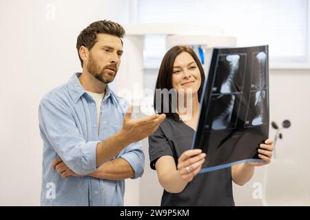 Männlicher Patient sieht mit einem Arzt auf Röntgenaufnahmen der Halswirbelsäule Stockfoto