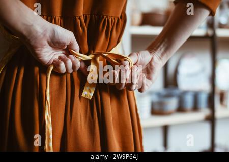 Potter Woman macht sich auf die Arbeit vor, indem sie eine Schürze aufzieht Stockfoto
