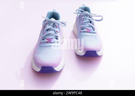 Violette blaue sportliche Laufschuhe für Frauen auf rosa Hintergrund. Mode, Trainingsschuhe für das Fitnessstudio, Schuhe für Damen. Nationalschuh Der Welttag Stockfoto