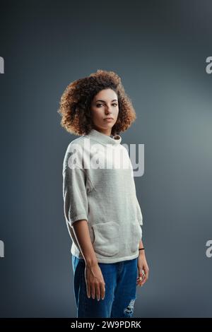 Reflektierend und ruhig erzählen der sanfte Blick und das lockige Haar der Frau eine Geschichte von ruhiger Kraft Stockfoto