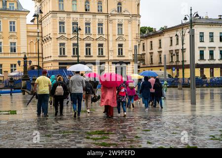An einem Herbsttag spazieren die Menschen durch das historische Zentrum der Stadt und schützen sich mit offenen Sonnenschirmen vor dem Regen. Stockfoto