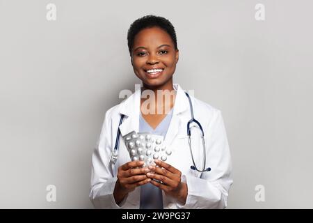 Lächelnder selbstbewusster Arzt und verschreibungspflichtige Medikamente für Patienten oder frei verkäufliche Pillen auf weißem Hintergrund. Ärztliche Apothekerberatung Stockfoto