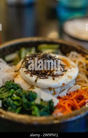 Koreanischer vegetarischer Bibimbap, gebratener Tofu und Gemüse in einer heißen Steinschale. Stockfoto