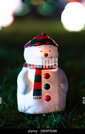 Das Bild einer kleinen weihnachtsdekoration - ein lächelnder Schneemann auf dem Geen Gras. Schneemann, der von innen leuchtet. Sehr lustiges Spielzeug. Hochauflösende vertikale Auflösung Stockfoto