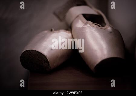 Pinkfarbene Ballettschuhe mit Bändern. Nahaufnahme und dunkler Hintergrund. Stockfoto